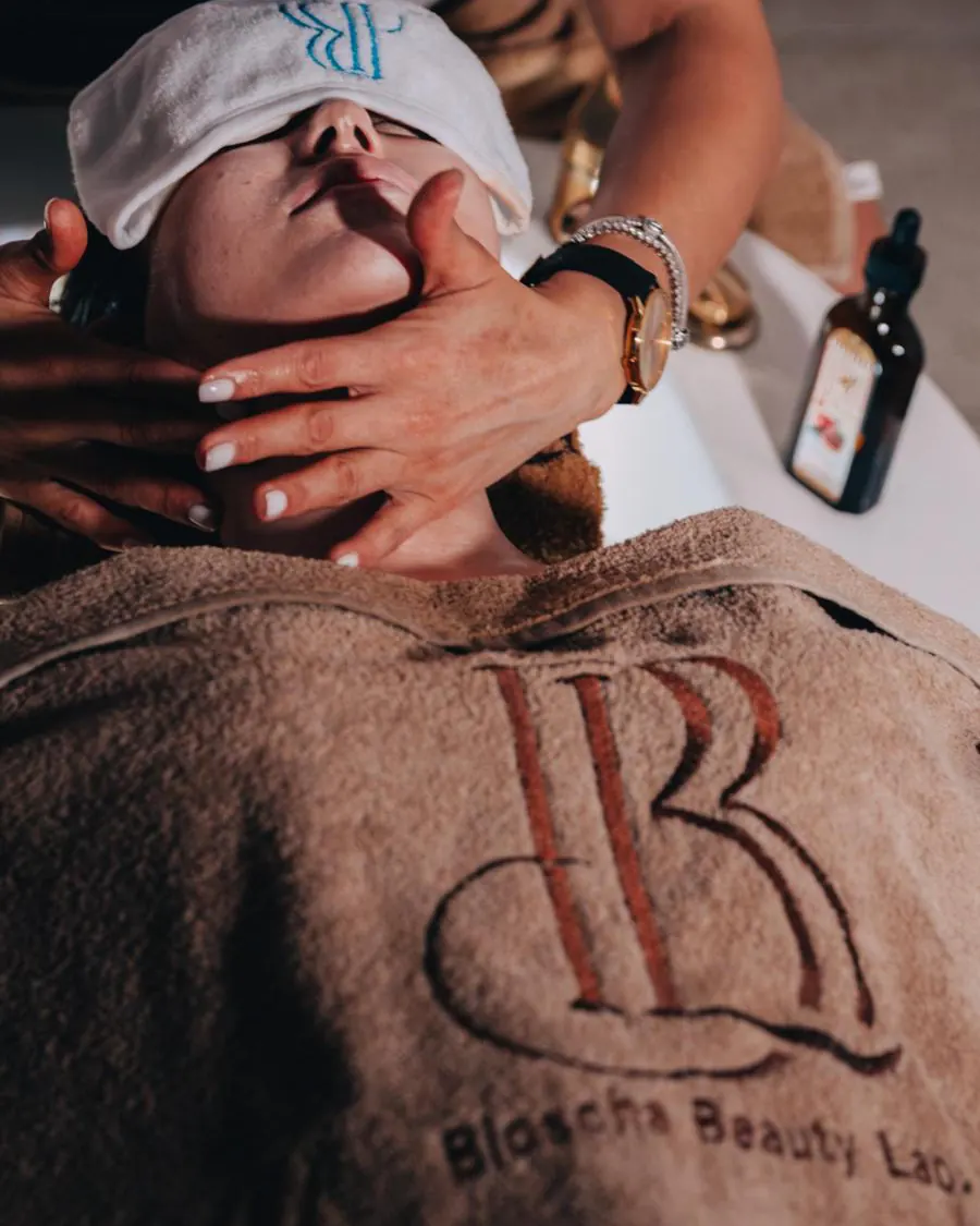 BIOSCHA Beauty Lab'da logolu havlu altında yüz ve boyun bakımı uygulaması